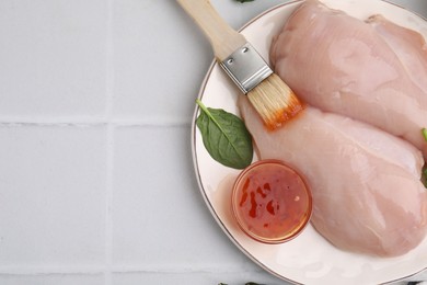 Photo of Marinade, basting brush and raw chicken fillets on white table, flat lay. Space for text