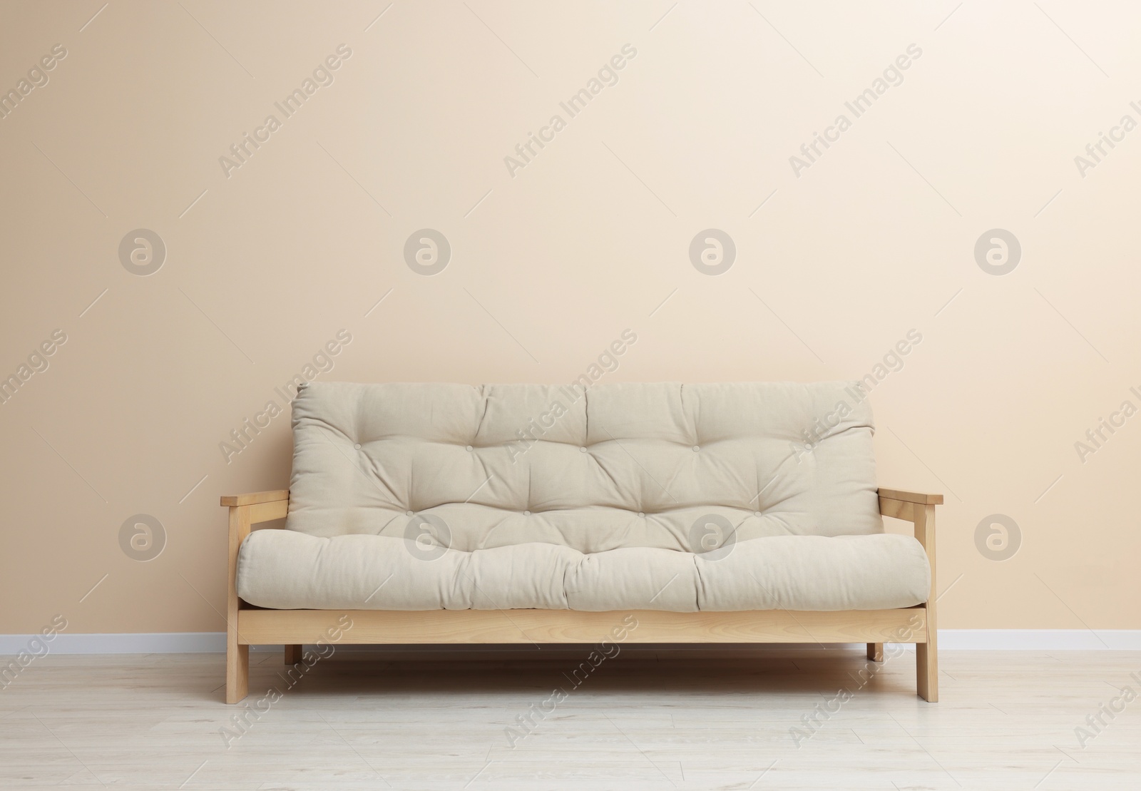 Photo of Comfortable sofa near beige wall on floor indoors