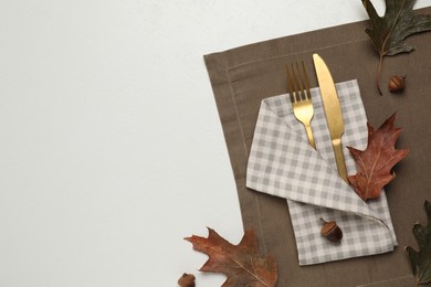 Photo of Cutlery, napkin and dry leaves on white background, flat lay with space for text. Table setting