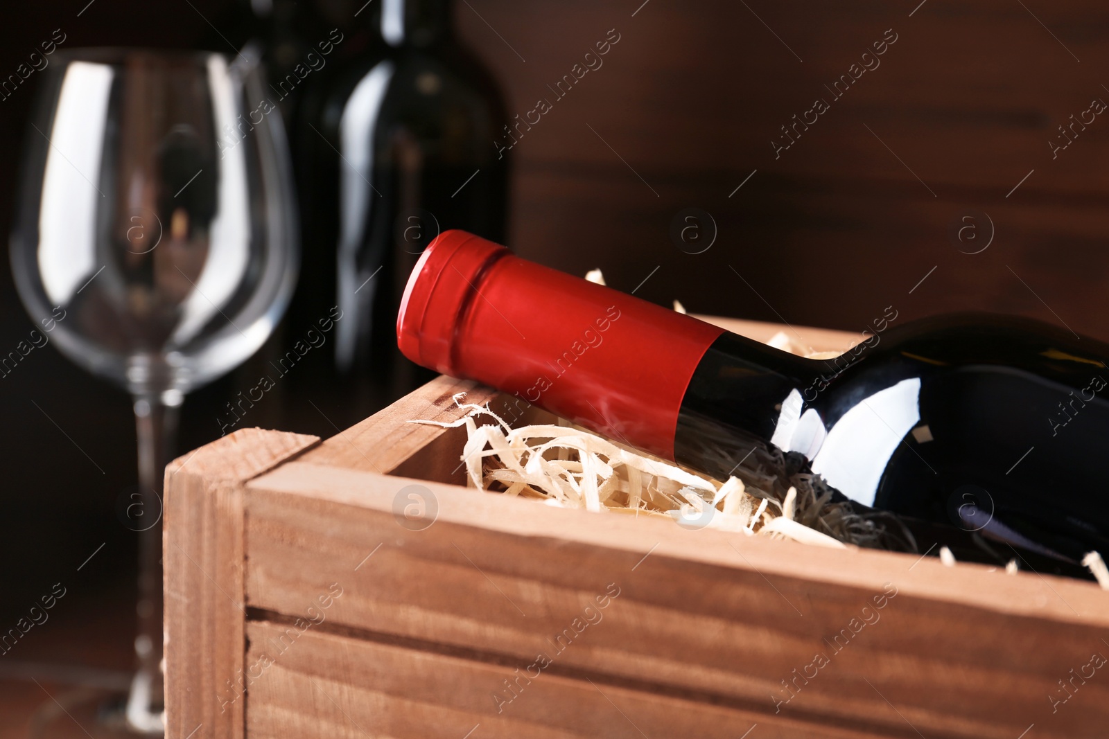 Photo of Open wooden crate with bottle of wine, closeup