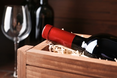 Open wooden crate with bottle of wine, closeup