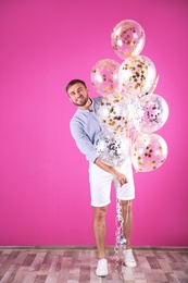 Young man with air balloons near color wall