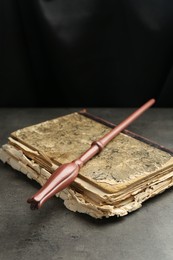 Magic wand and old book on light grey table