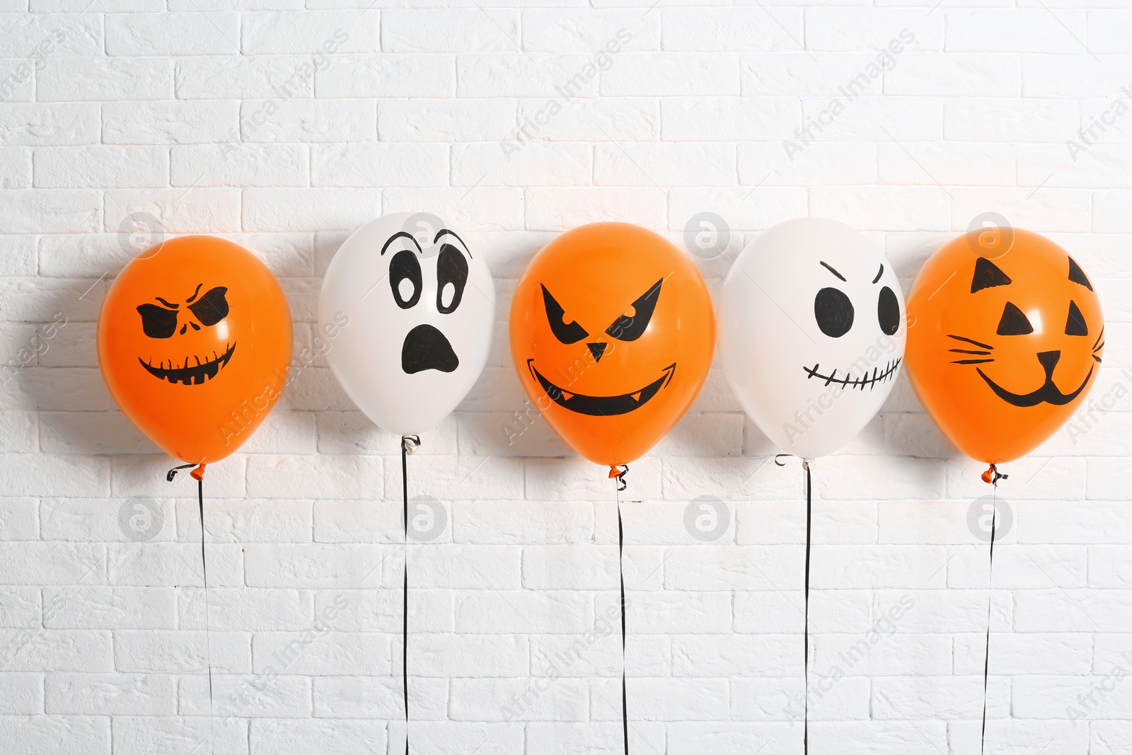 Photo of Color balloons for Halloween party against white brick wall