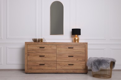 Photo of Stylish room interior with chest of drawers, mirror and decor elements
