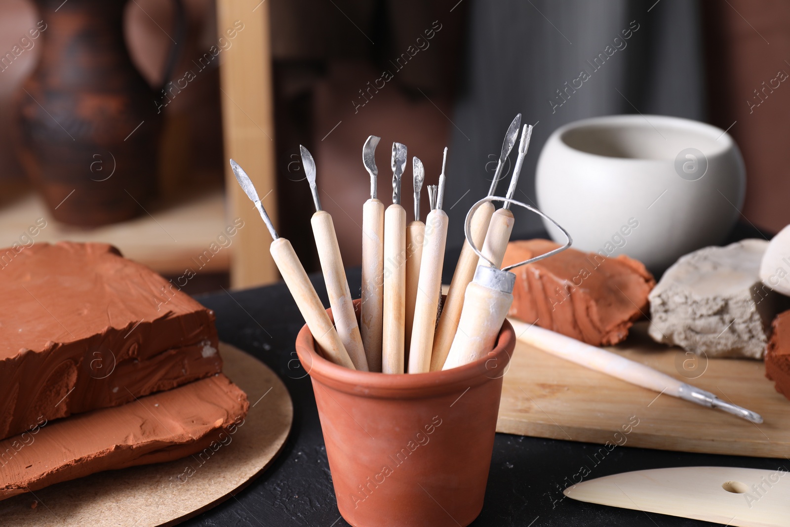 Photo of Clay and set of modeling tools on table in workshop