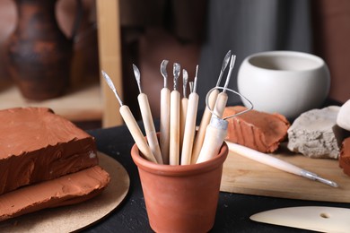 Photo of Clay and set of modeling tools on table in workshop