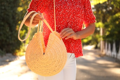 Photo of Young woman with stylish straw bag in park, closeup
