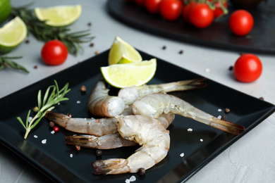Photo of Fresh raw shrimps with lime and rosemary on plate, closeup
