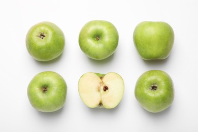 Photo of Whole and cut green apples on white background, flat lay