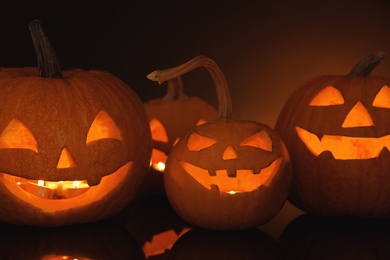 Photo of Halloween pumpkin heads. Glowing jack lanterns on dark background