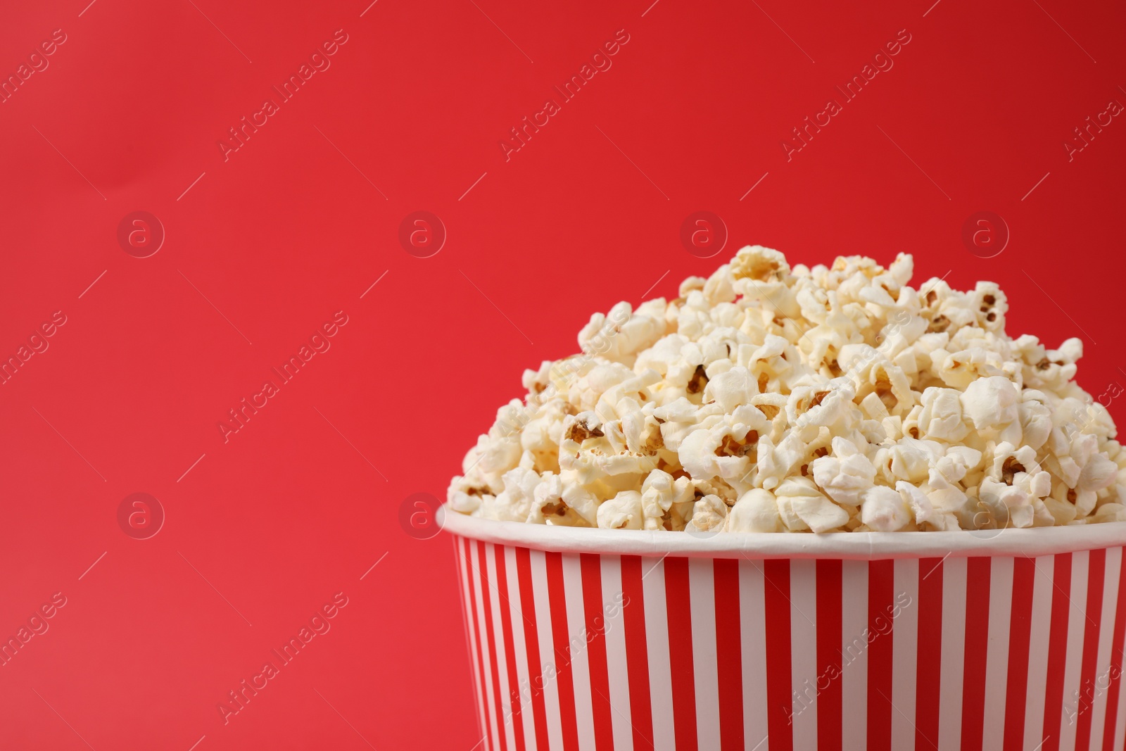Photo of Delicious popcorn on red background, closeup. Space for text