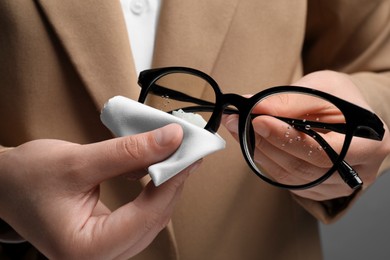 Photo of Woman wiping her glasses with microfiber cloth, closeup