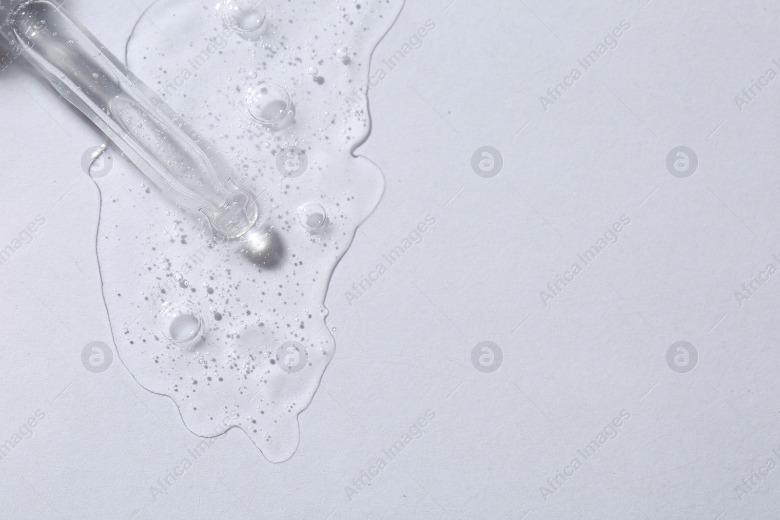 Photo of Pipette with cosmetic serum on white background, top view. Space for text