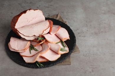 Photo of Delicious cut ham with rosemary on grey table, space for text
