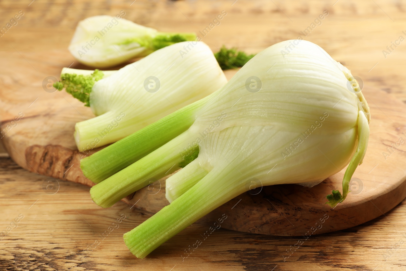 Photo of Fresh raw fennel bulbs on wooden table, closeup