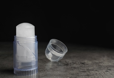 Photo of Natural crystal alum deodorant and cap on grey table, space for text