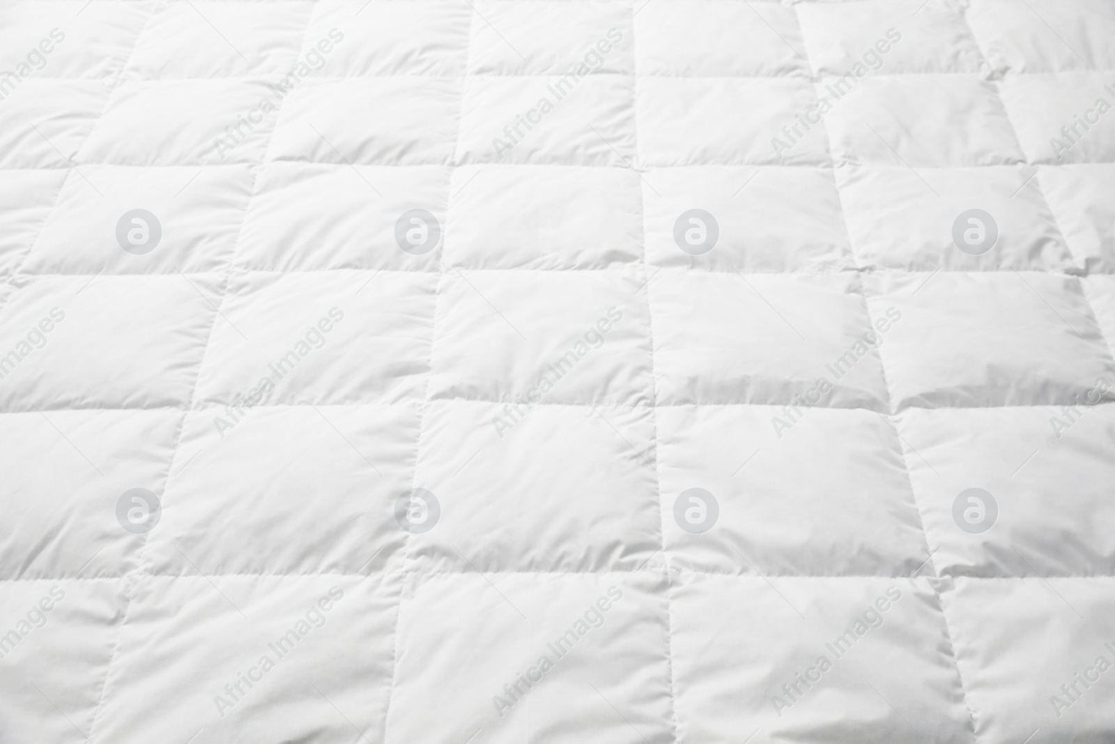 Photo of Soft quilted blanket as background, closeup view