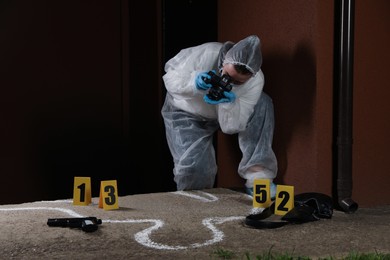 Photo of Criminologist in protective suit working at crime scene outdoors. Space for text