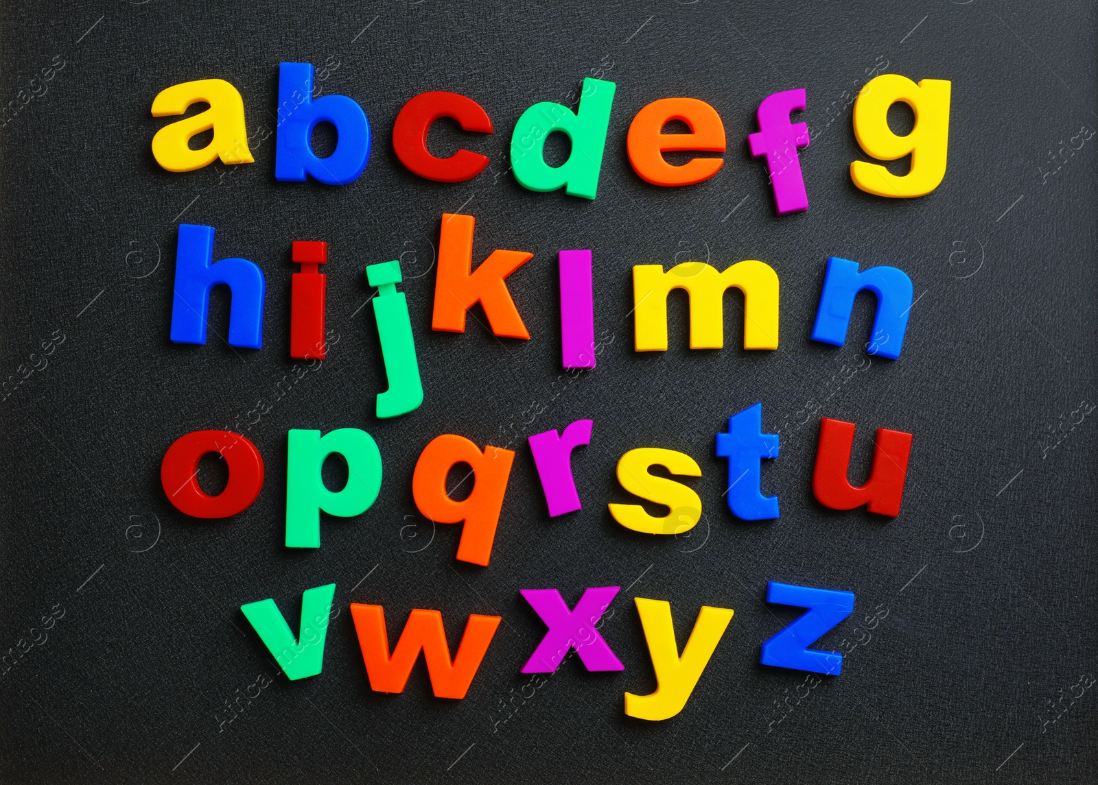 Photo of Colorful plastic magnetic letters on black background, top view. Alphabetical order