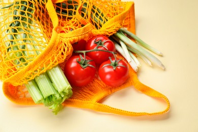 String bag with different vegetables on beige background, closeup