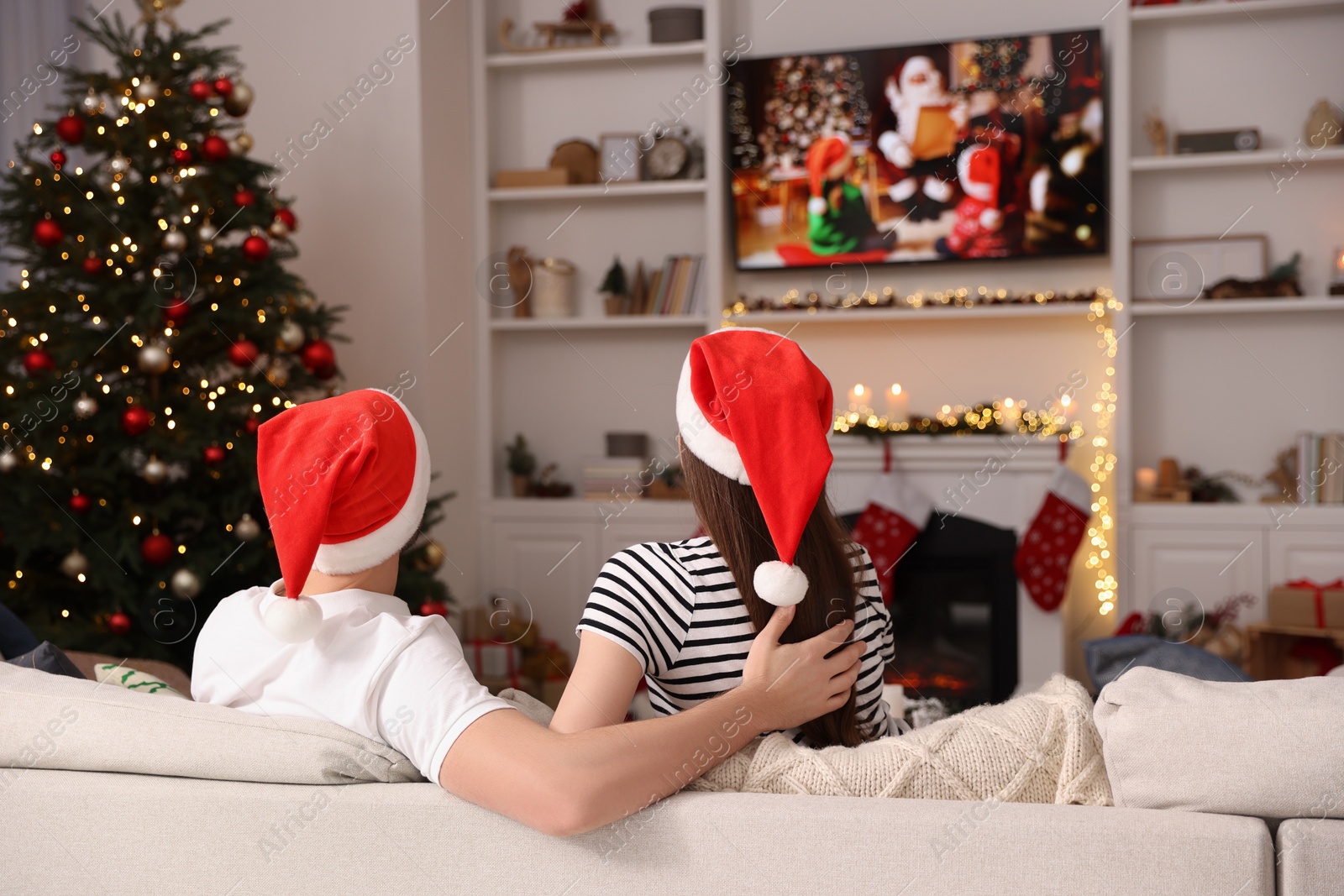 Photo of Couple watching Christmas movie via TV in cosy room, back view. Winter holidays atmosphere