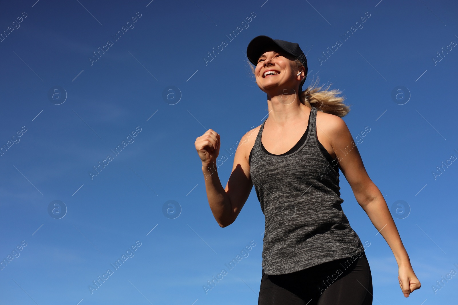 Photo of Woman listening to music while running outdoors in morning, low angle view. Space for text