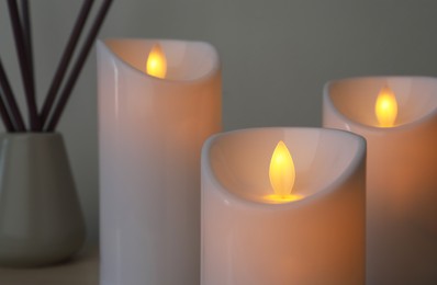 Photo of Glowing decorative LED candles on grey background, closeup view