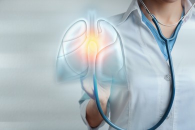 Doctor with stethoscope and digital image of human lungs on light background, closeup