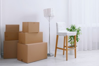 Photo of Boxes, lamp and chair wrapped in stretch film indoors