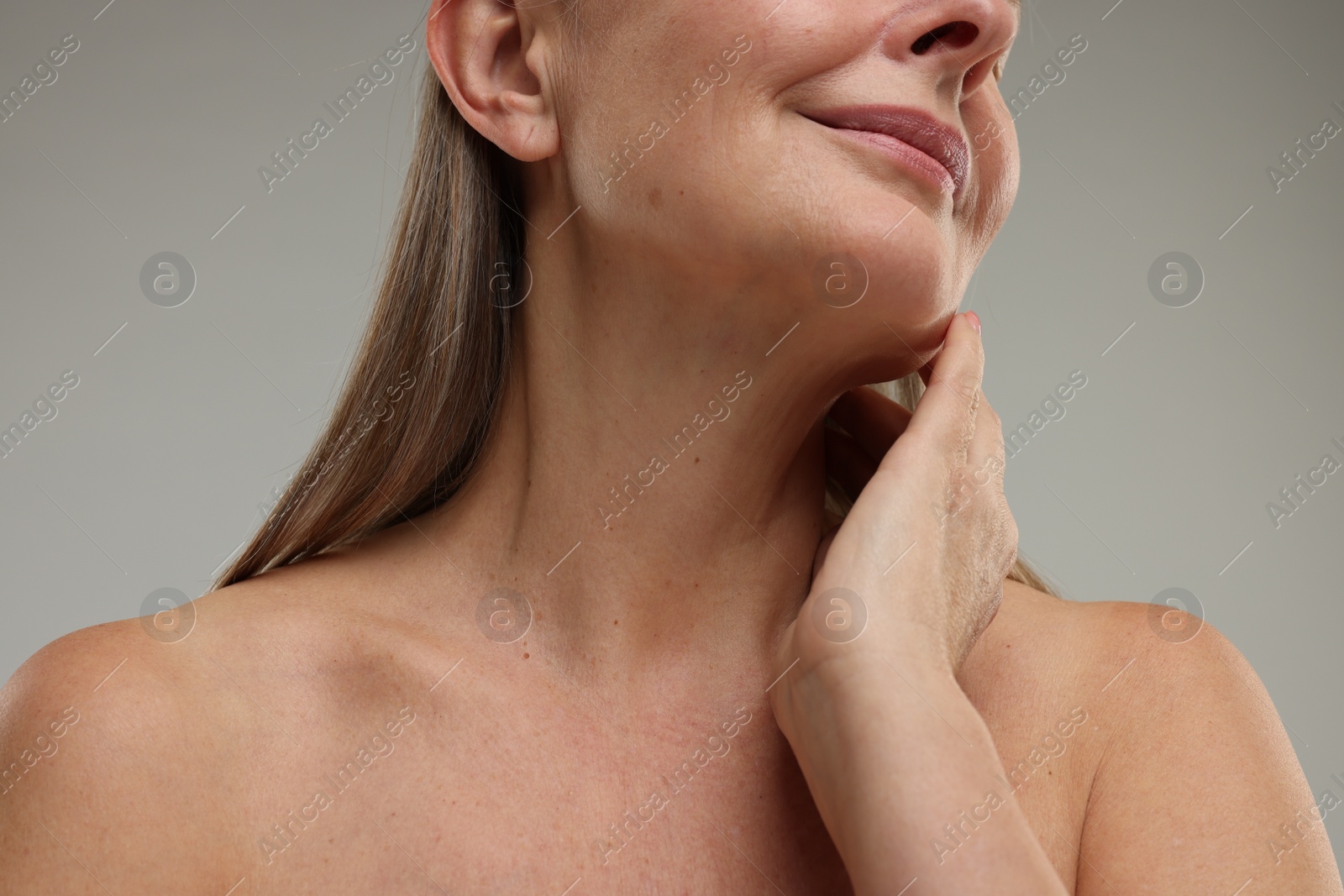 Photo of Mature woman touching her neck on grey background, closeup