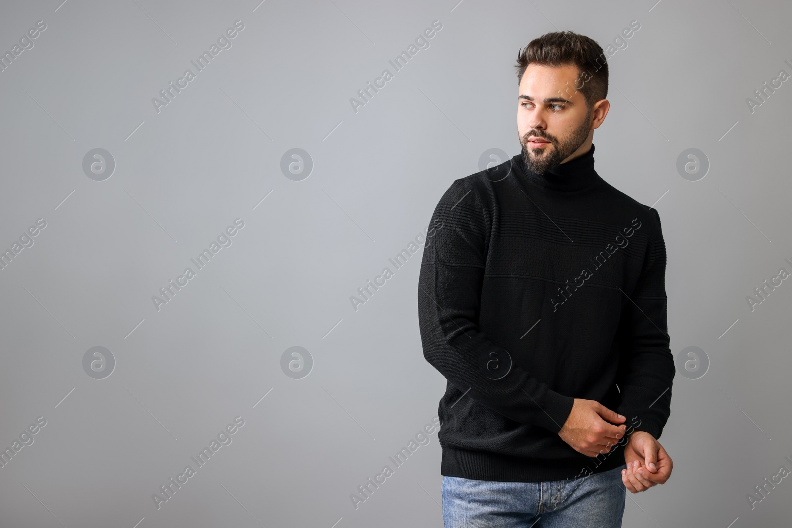 Photo of Handsome man in stylish black sweater on grey background, space for text