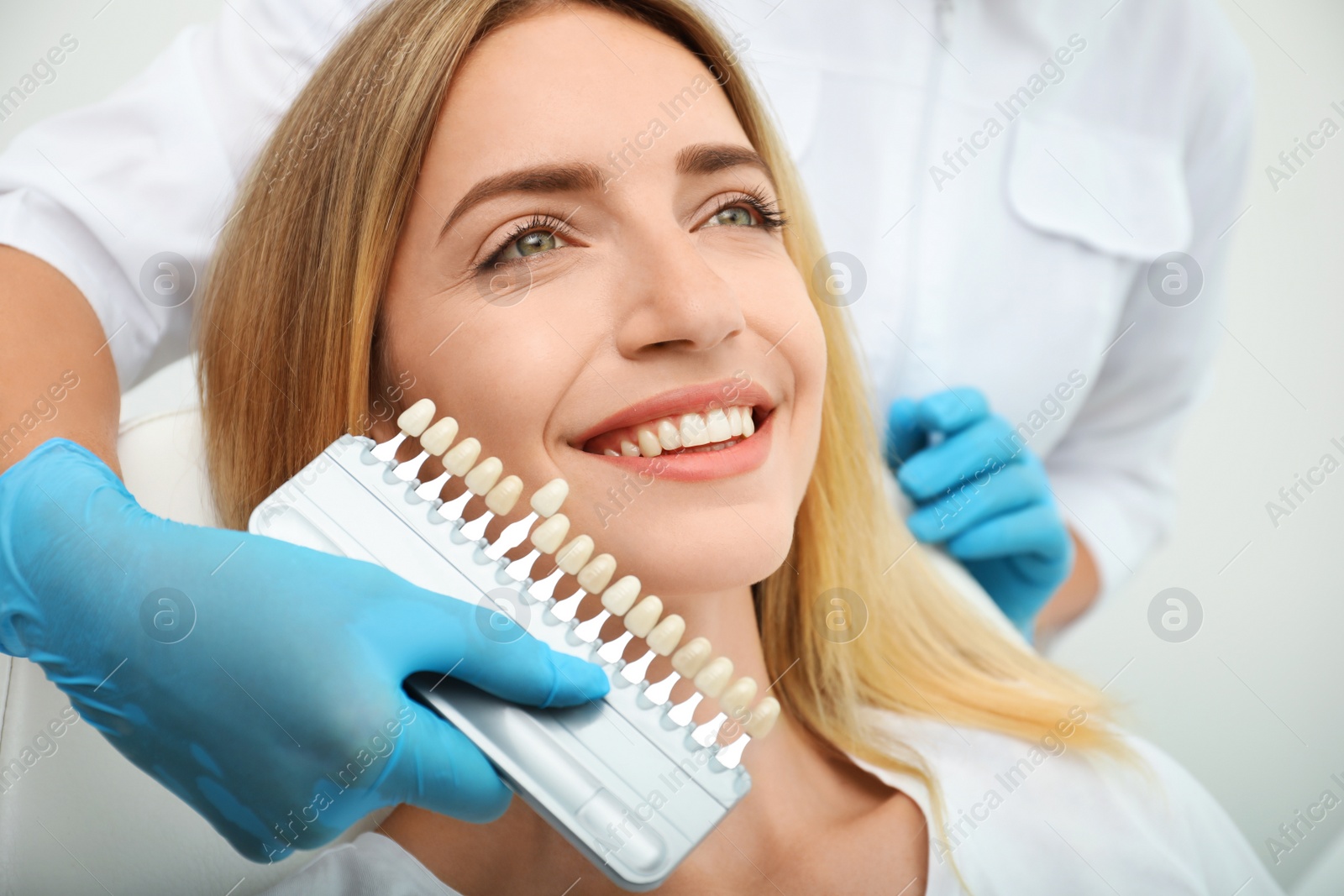 Photo of Doctor matching patient's teeth color with palette, closeup. Cosmetic dentistry