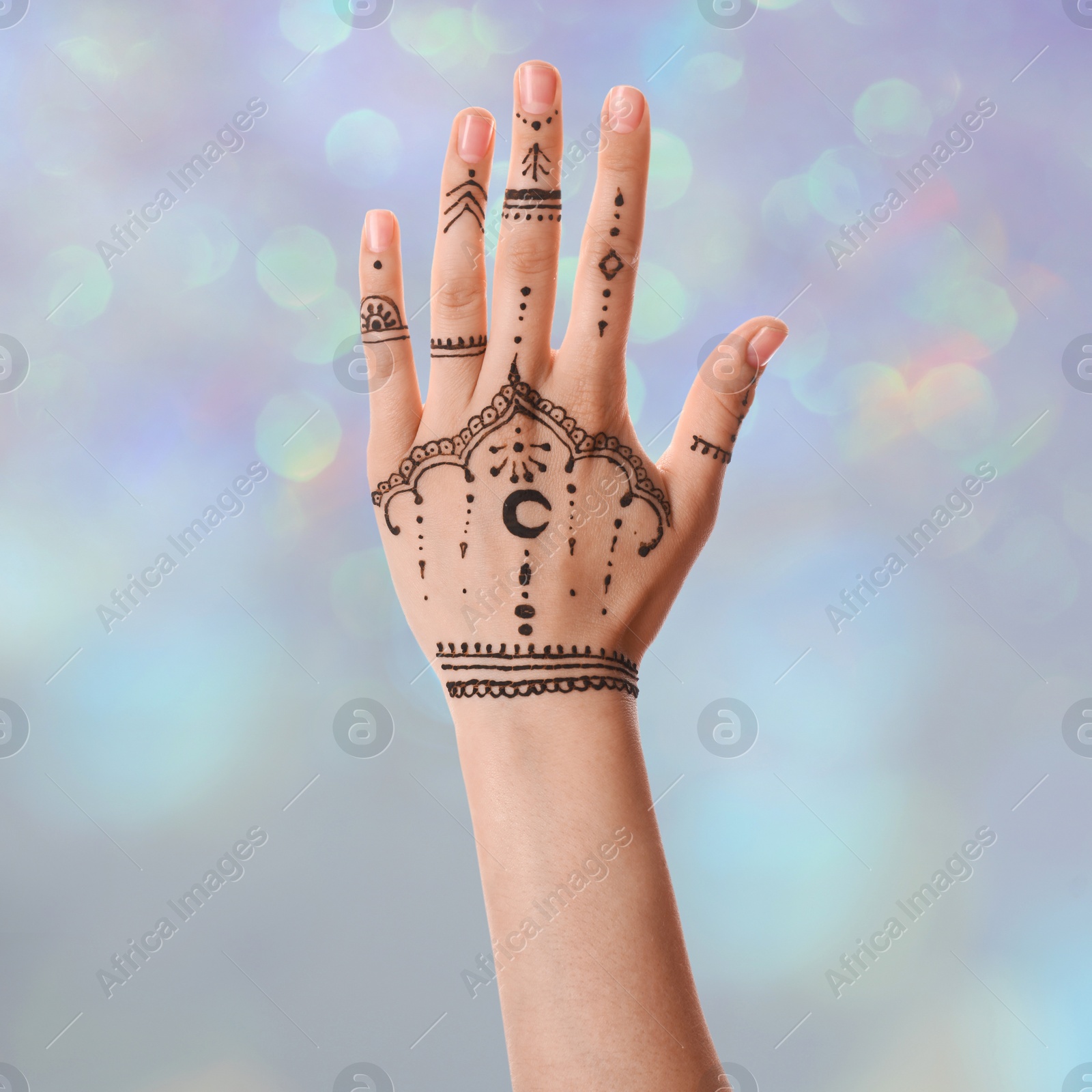 Image of Woman with henna tattoo on hand against blurred lights, bokeh effect