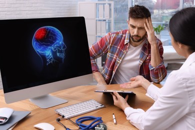 Young neurologist consulting patient at table in clinic