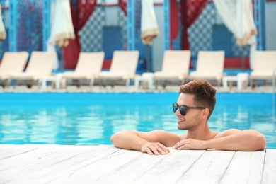 Photo of Handsome young man in swimming pool on sunny day