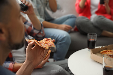 Photo of Man eating pizza with friends indoors, closeup