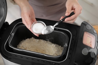 Making dough. Woman adding salt into breadmaker machine, closeup