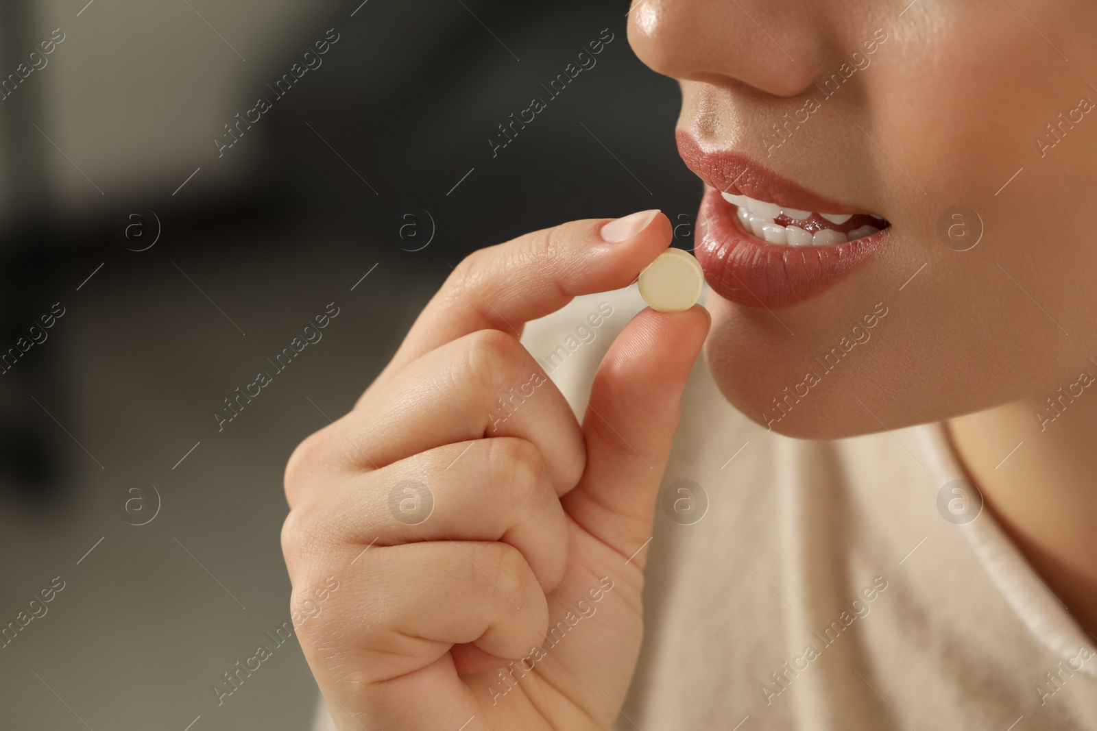 Photo of Young woman taking dietary supplement pill, closeup