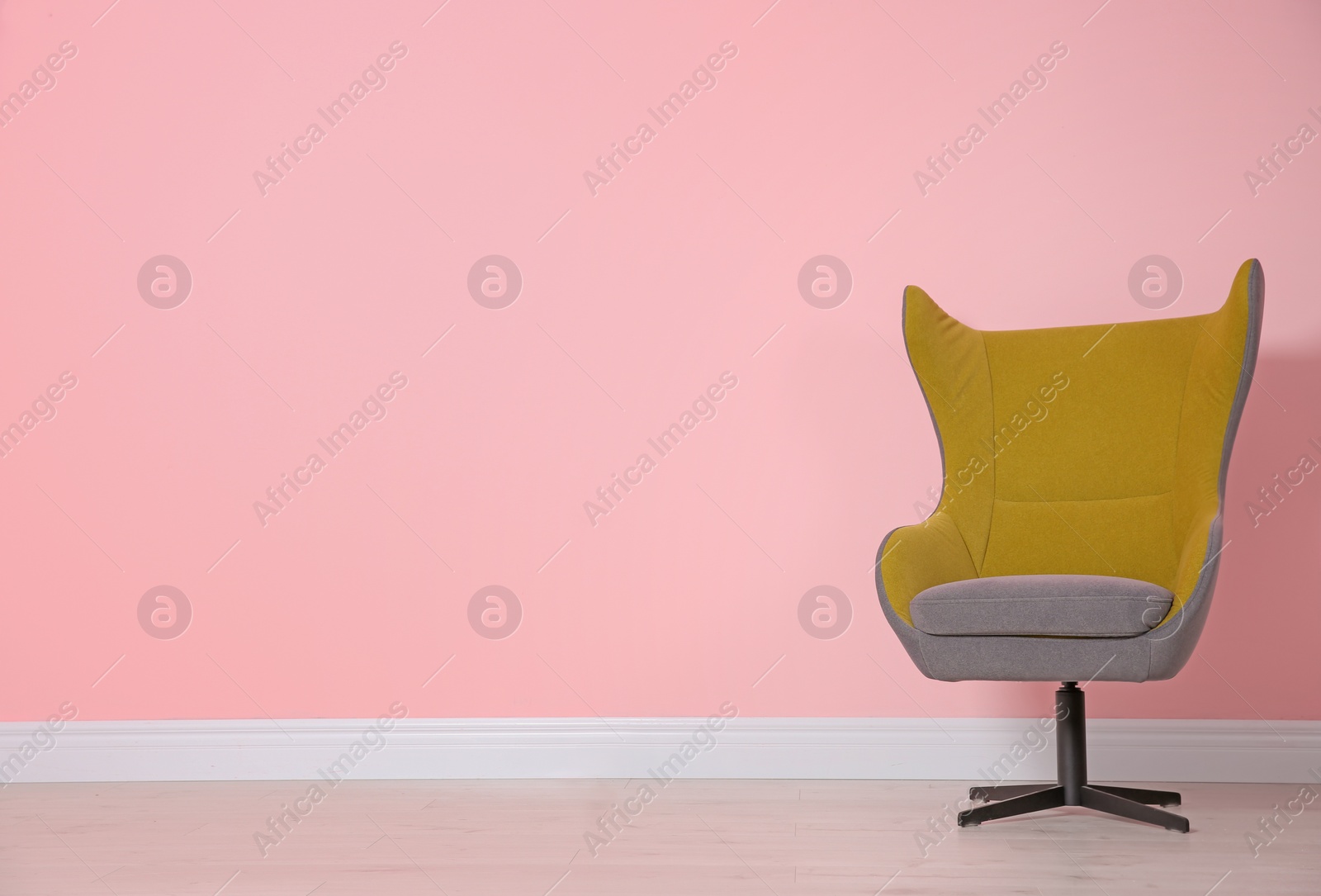 Photo of Comfortable armchair near color wall. Modern interior element