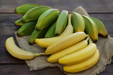 Photo of Different sorts of bananas on wooden table, closeup