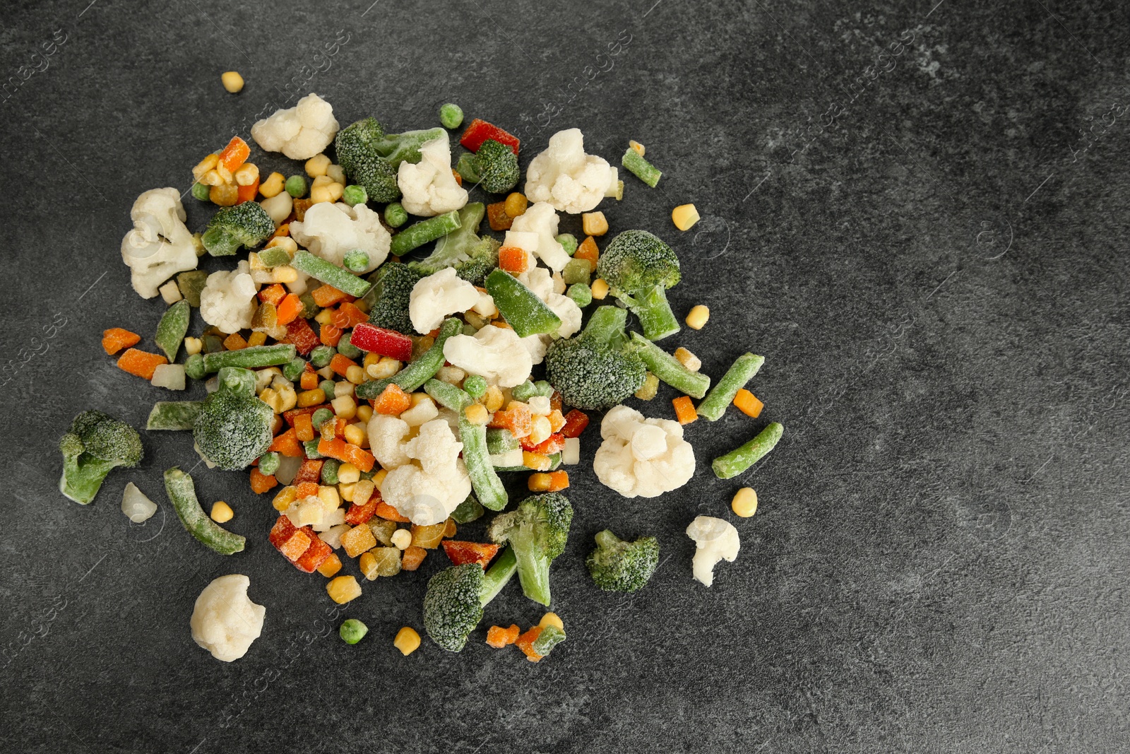 Photo of Mix of different frozen vegetables on gray table, top view. Space for text