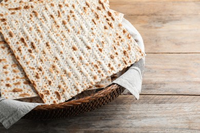 Photo of Traditional matzos in basket on wooden table, closeup