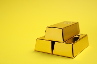 Photo of Stack of shiny gold bars on yellow background. Space for text