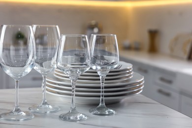 Photo of Clean glasses, dishware and cutlery on white marble table in kitchen