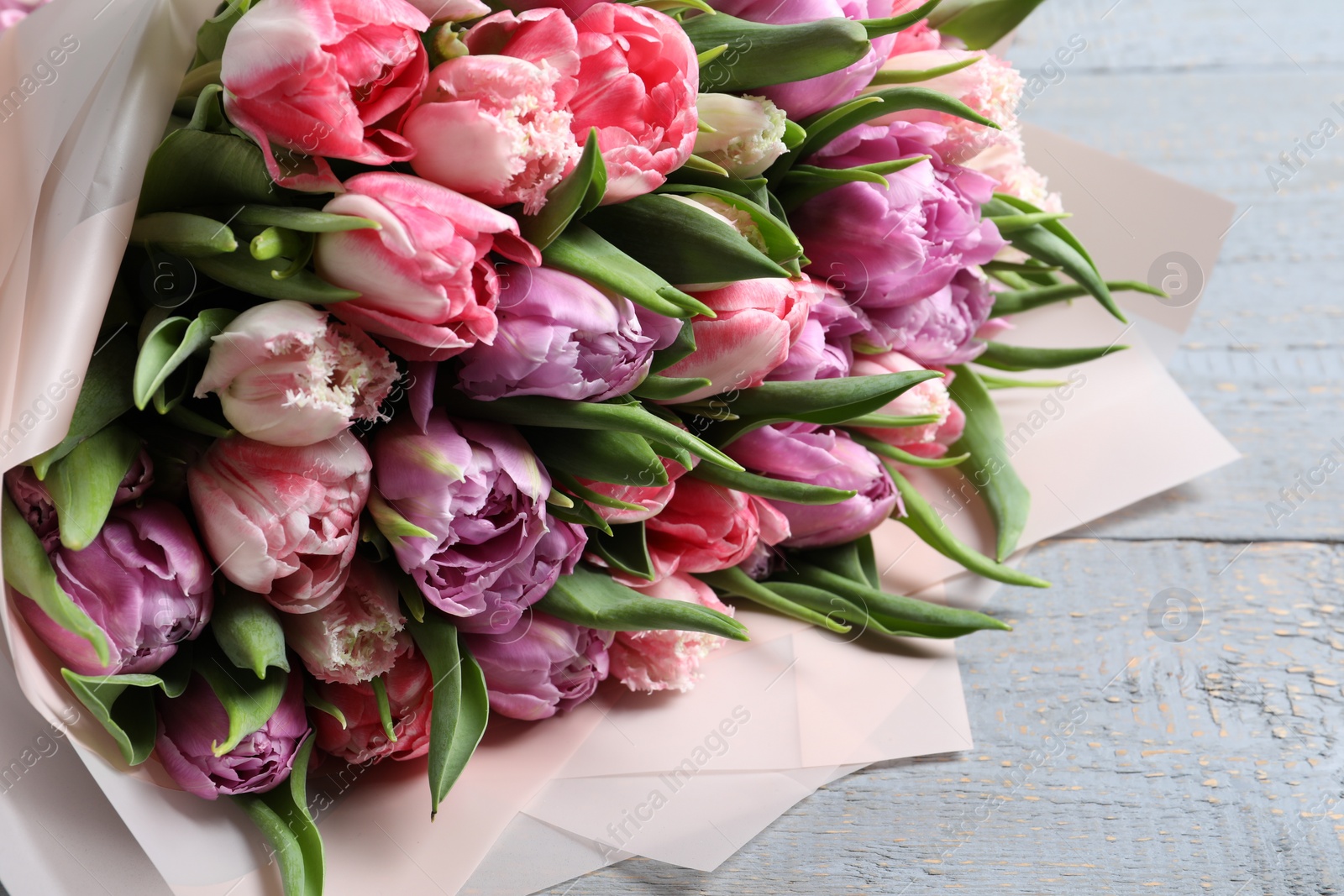 Photo of Bouquet of beautiful tulips on grey wooden table, closeup