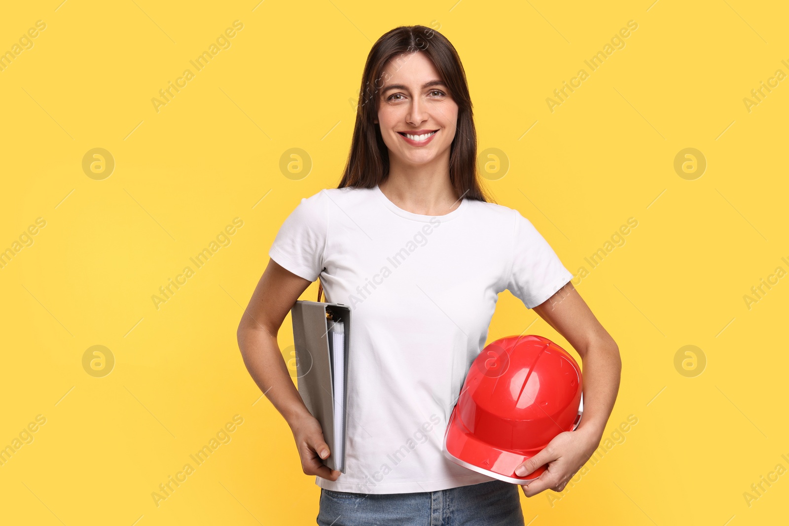 Photo of Architect with hard hat and folder on yellow background