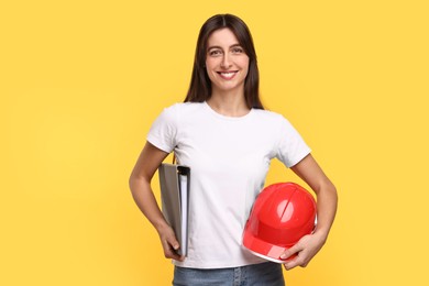 Photo of Architect with hard hat and folder on yellow background