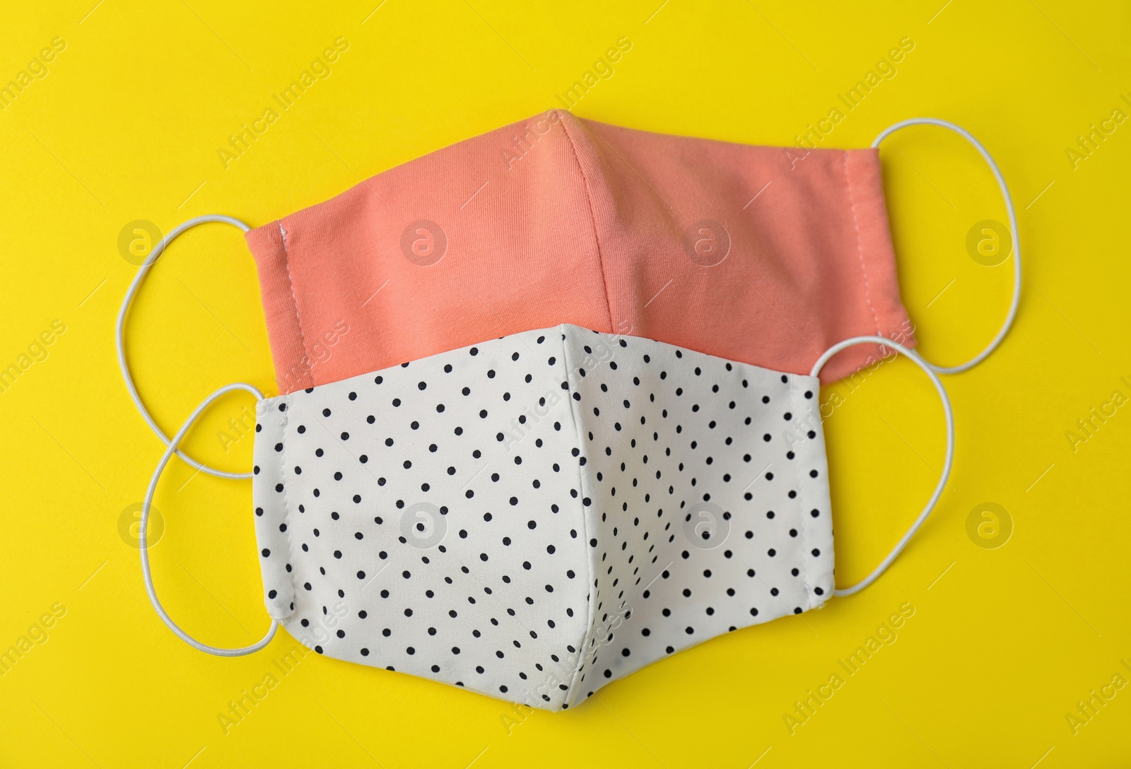 Photo of Homemade protective face masks on yellow background, flat lay