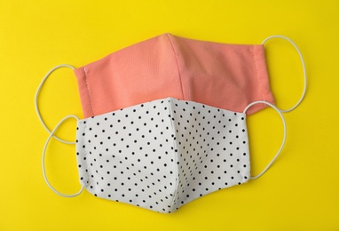 Photo of Homemade protective face masks on yellow background, flat lay